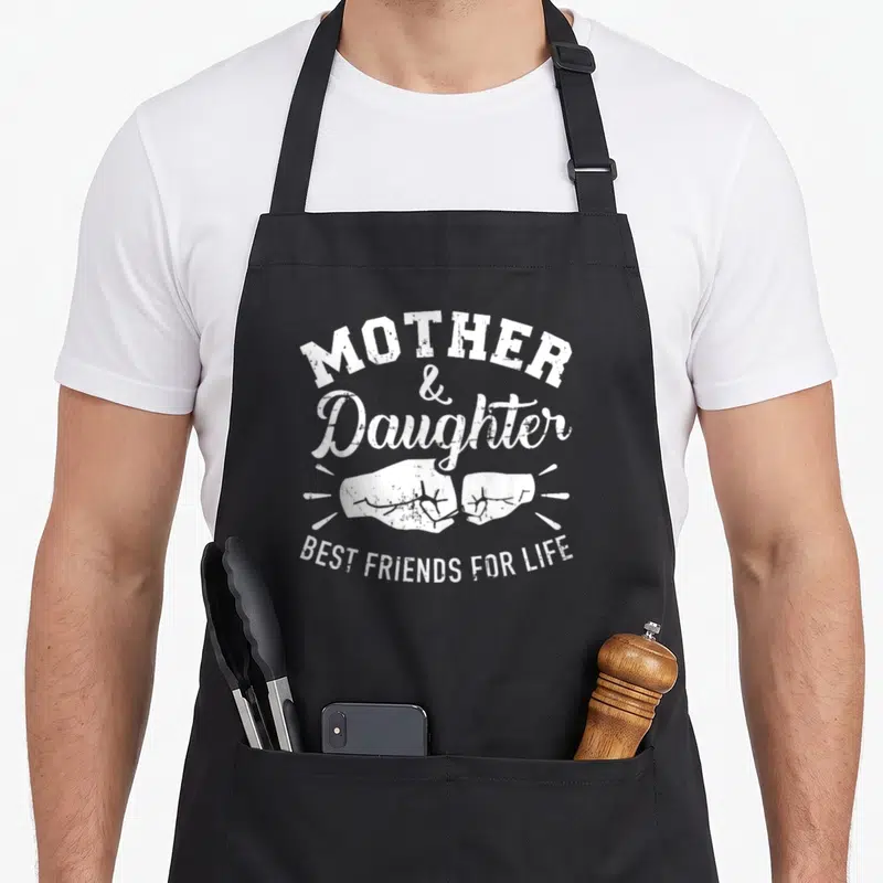 Friend mother daughter apron - White distressed two fists bumping with MOTHER Daughter BEST FRIENDS FOR LIFE text — shown on a black cotton canvas apron against a white background