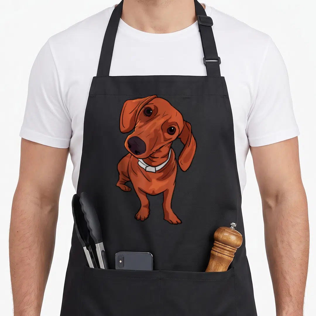 Funny dog dachshund apron - Brown cartoon dachshund wearing a white collar standing on grey background — shown on a black cotton canvas apron against a white background