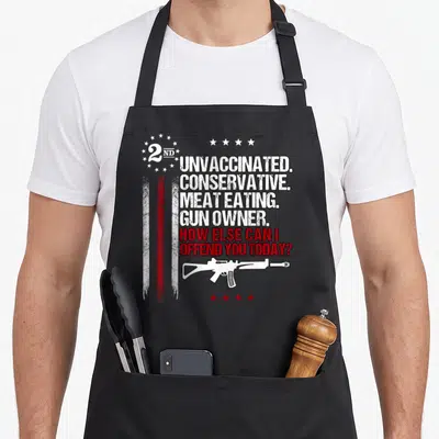Unvaccinated meat aprons - Stacked white text reading unvaccinated conservative meat eating gun owner above a rifle — shown on a black cotton canvas apron against a white background