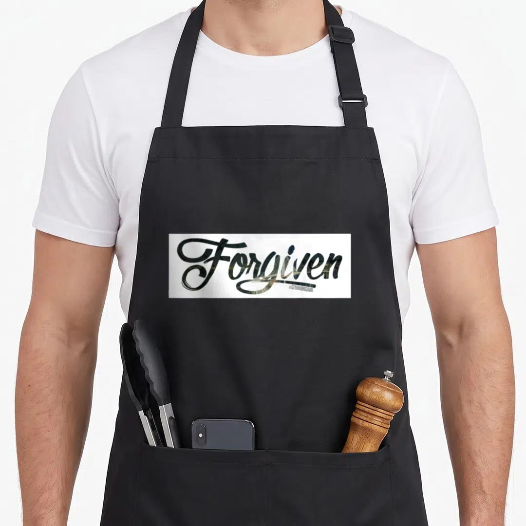 Gttmh christian apron - Forgiven script text with #GTTMHOIGINAL hashtag on white background — shown on a black cotton canvas apron against a white background