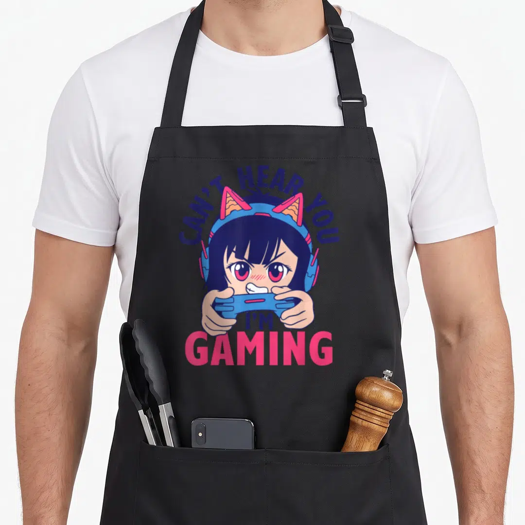 Hear anime apron - Cartoon girl with cat headphones holding controller under arched text Can't Hear You I'm Gaming — shown on a black cotton canvas apron against a white background