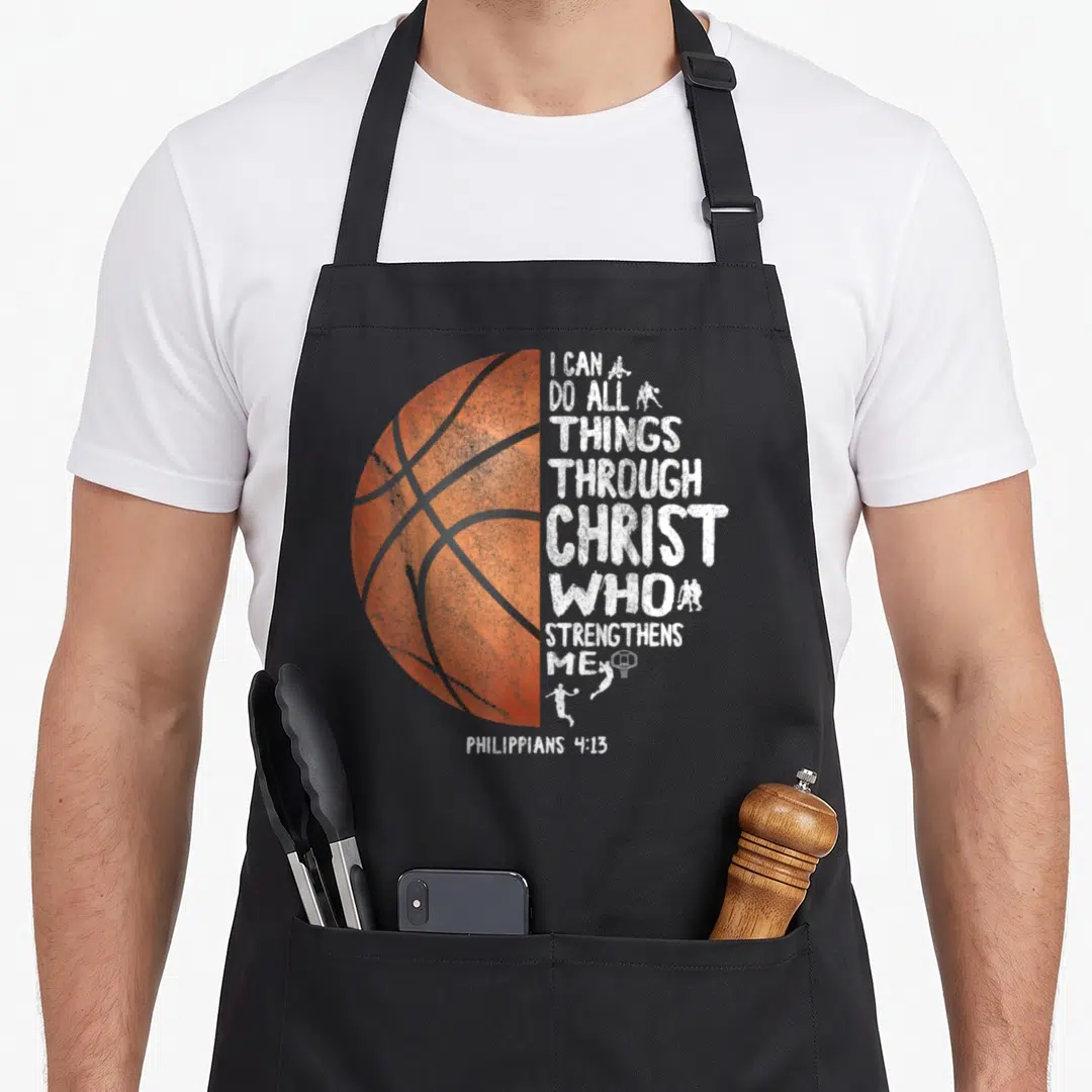 Through basketball boys apron - Distressed orange half-basketball with stacked white I Can Do All Things Through Christ — shown on a black cotton canvas apron against a white background