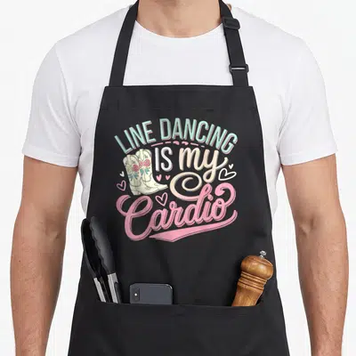 Cardio line apron - Mint green text Line Dancing Is My Cardio with cream cowboy boots and pink hearts — shown on a black cotton canvas apron against a white background