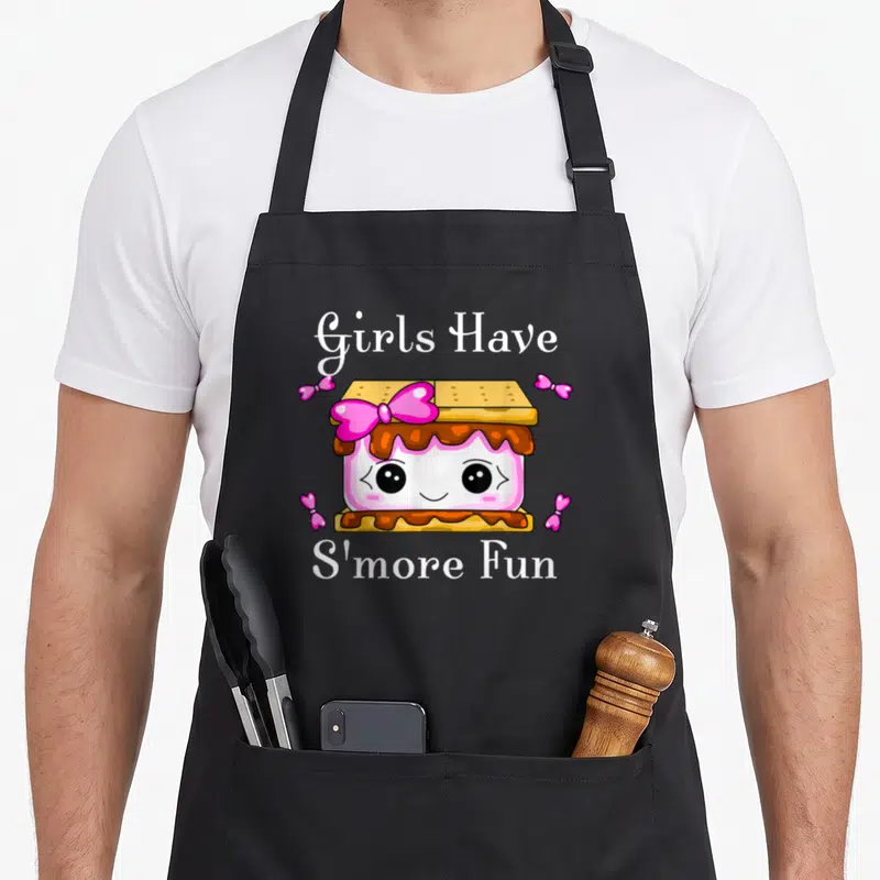 Cute smore camping apron - Cartoon s'more with pink bow and white text Girls Have S'more Fun — shown on a black cotton canvas apron against a white background