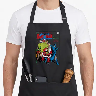 Greeting christmas robin apron - Vintage Batman comic cover with Santa, War Loan text, and cartoon characters in red — shown on a black cotton canvas apron against a white background