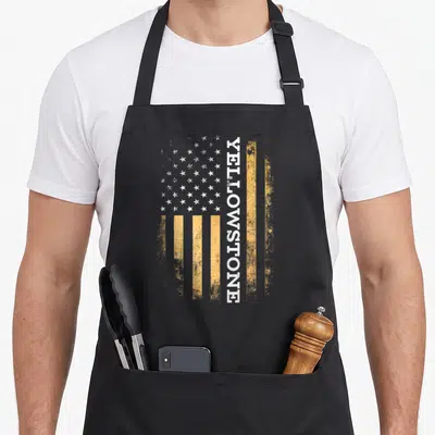 Funny stone apron - Distressed yellow and white flag with vertical Yellowstone text — shown on a black cotton canvas apron against a white background