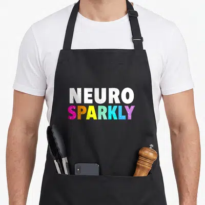 Neuro sparkly aprons - Stacked NEURO SPARKLY text in white and rainbow colors with speckled texture — shown on a black cotton canvas apron against a white background