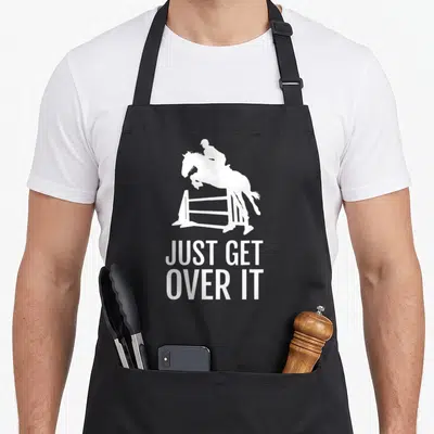 Show horse apron - White silhouette of horse jumping fence above text Just Get Over It — shown on a black cotton canvas apron against a white background