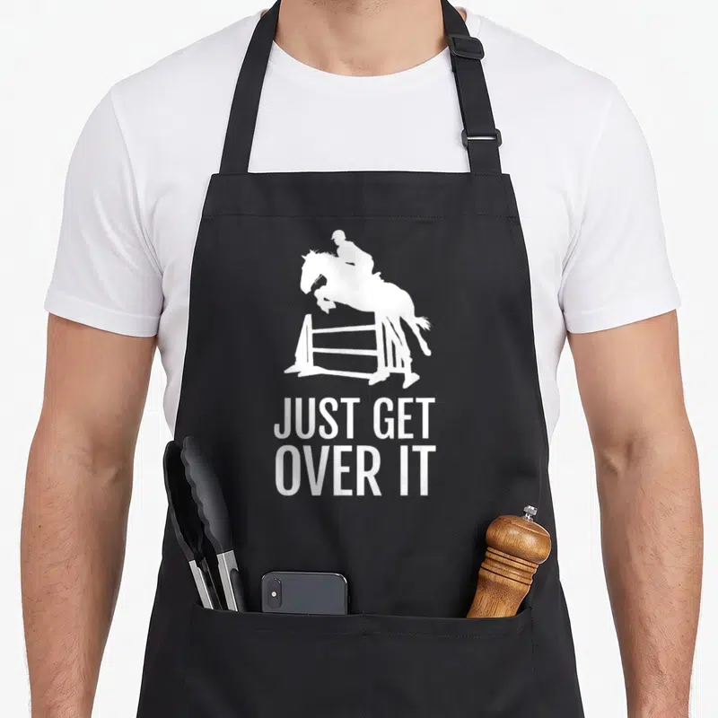 Show horse apron - White silhouette of horse jumping fence above text Just Get Over It — shown on a black cotton canvas apron against a white background