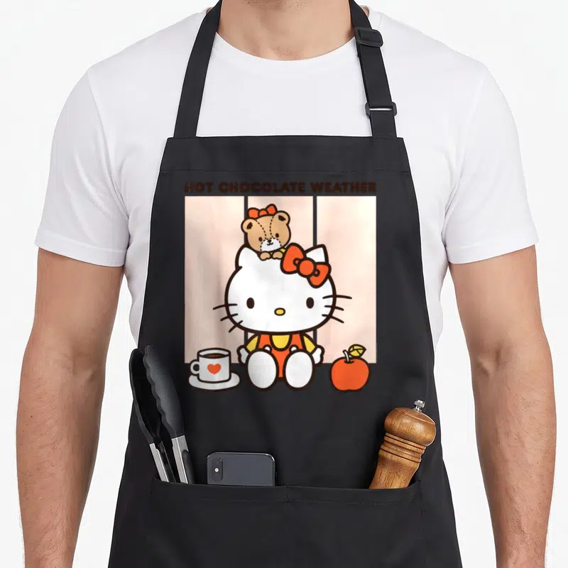 Hot chocolate apron - Hello Kitty with teddy bear cup and apple on pink striped background under hot chocolate weather — shown on a black cotton canvas apron against a white background