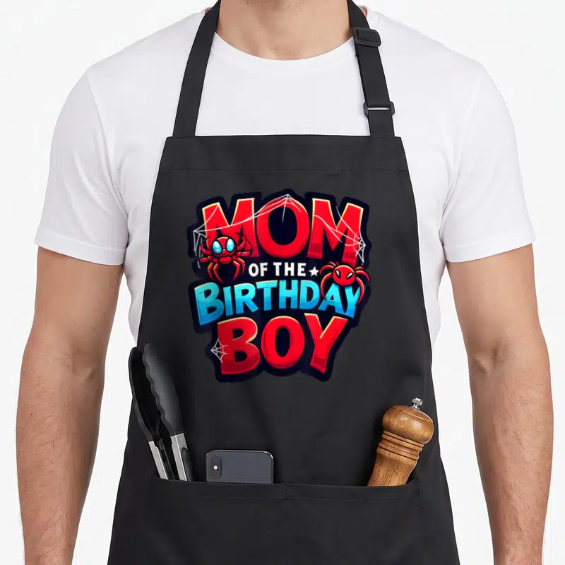 Mum family reunion aprons - MOM OF THE BIRTHDAY BOY text with red spiders and webs on black background — shown on a black cotton canvas apron against a white background