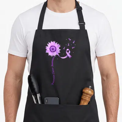 Pancreatic cancer ribbon apron - Purple sunflower with extending ribbon and vertical Awareness text — shown on a black cotton canvas apron against a white background