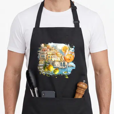 Amalfi italy apron - Watercolor Amalfi Coast town with cocktail glass and lemon branch overlay — shown on a black cotton canvas apron against a white background