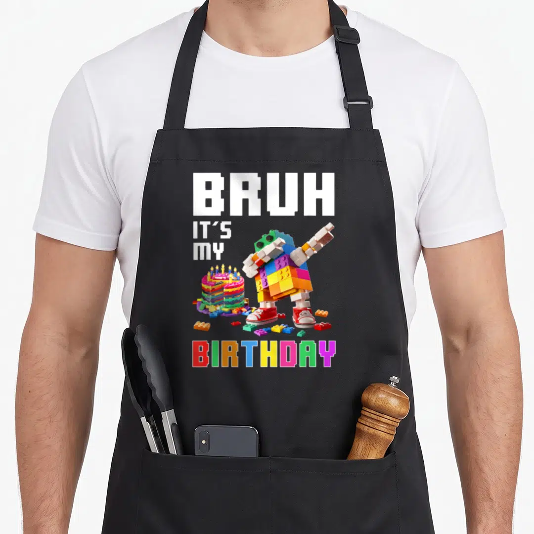 Bruh block & apron - Pixel robot dabbing next to rainbow birthday cake with blocky text — shown on a black cotton canvas apron against a white background