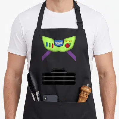 Cute costume halloween apron - Lime green Buzz Lightyear chest plate with wing emblem, colored buttons, purple straps — shown on a black cotton canvas apron against a white background