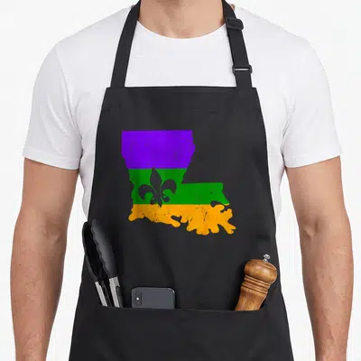 Distressed mardi gras aprons - Louisiana map shape with purple, green, and orange stripes and a fleur-de-lis — shown on a black cotton canvas apron against a white background