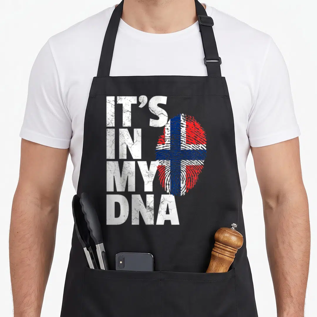 Dna norwegian kitchen aprons - Stacked white text IT'S IN MY DNA next to a red white and blue fingerprint flag — shown on a black cotton canvas apron against a white background