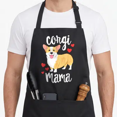 Corgi dog apron - Cartoon corgi with red hearts and Corgi Mama text — shown on a black cotton canvas apron against a white background