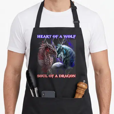 Wolf dragon apron - Realistic dragon and wolf facing each other with moon and lightning beneath HEART OF A WOLF SOUL — shown on a black cotton canvas apron against a white background
