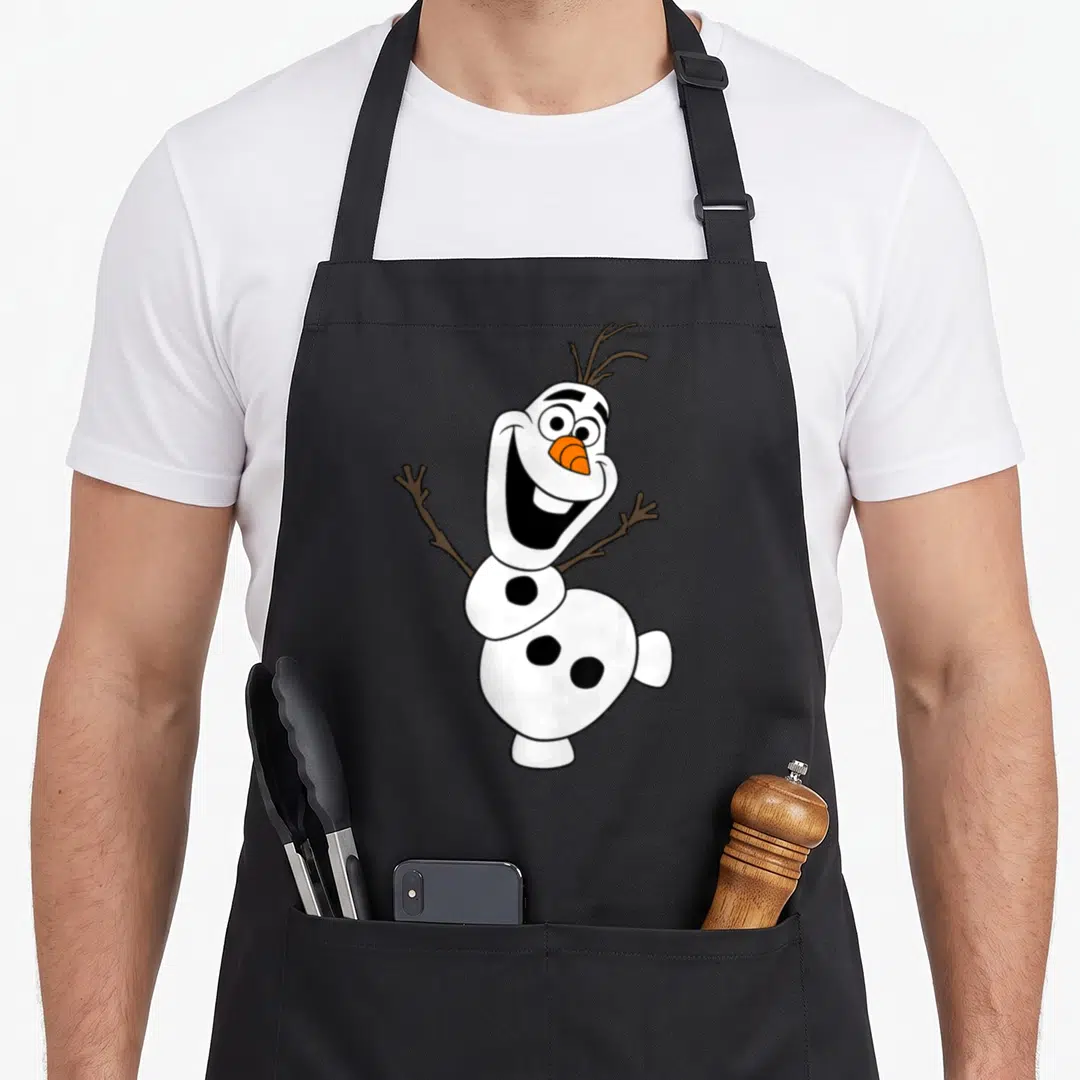 Pose snowman apron - Cartoon snowman with orange nose and brown stick arms smiling widely — shown on a black cotton canvas apron against a white background