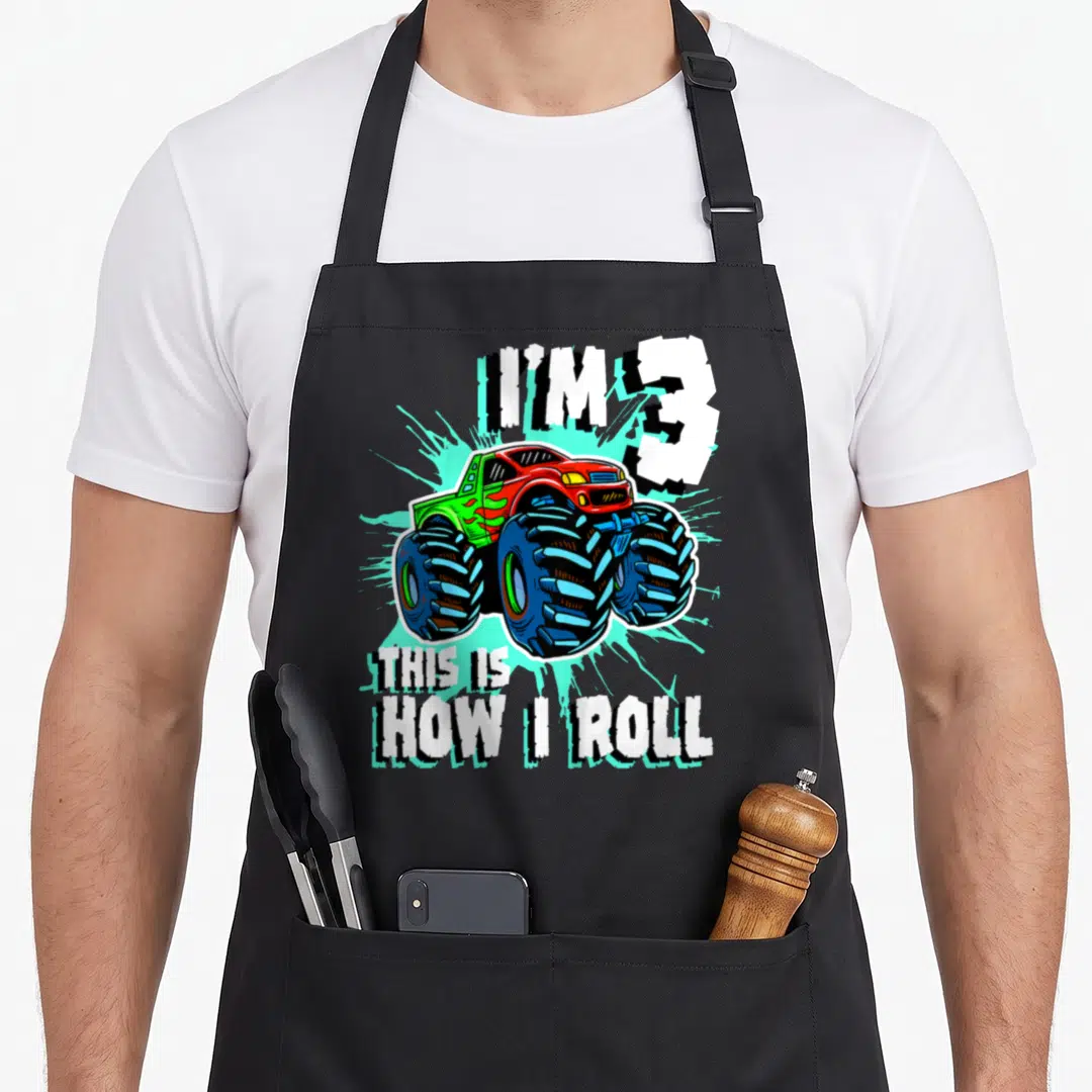 Birthday 3rd truck apron - Red monster truck with I'M 3 THIS IS HOW I ROLL text over light blue splatter — shown on a black cotton canvas apron against a white background
