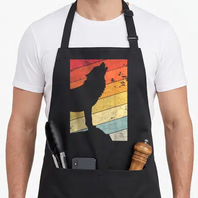 Cute wolf apron - Grey wolf silhouette against horizontal stripes in red, orange, yellow, blue on black bib apron — shown on a black cotton canvas apron against a white background