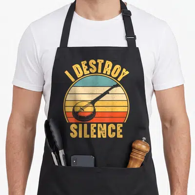 Player banjo apron - Banjo over striped yellow orange red blue sun with I Destroy Silence text — shown on a black cotton canvas apron against a white background