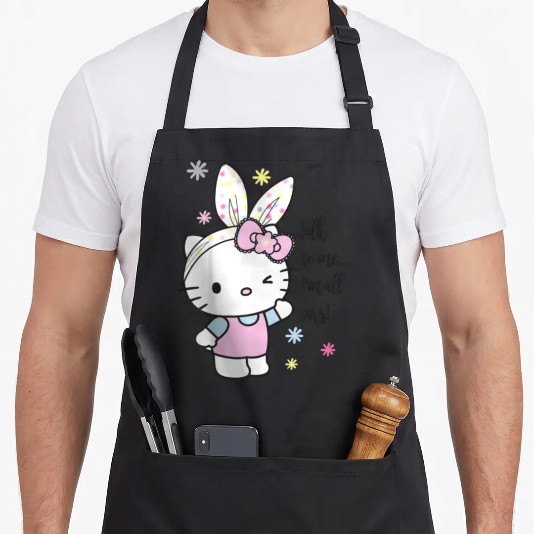 Talk easter apron - Hello Kitty in bunny ears with Talk to me I'm all ears text and flowers — shown on a black cotton canvas apron against a white background