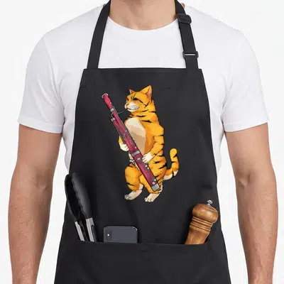 Bassoon cat apron - Orange tabby cat standing and playing a red bassoon instrument in cartoon style — shown on a black cotton canvas apron against a white background