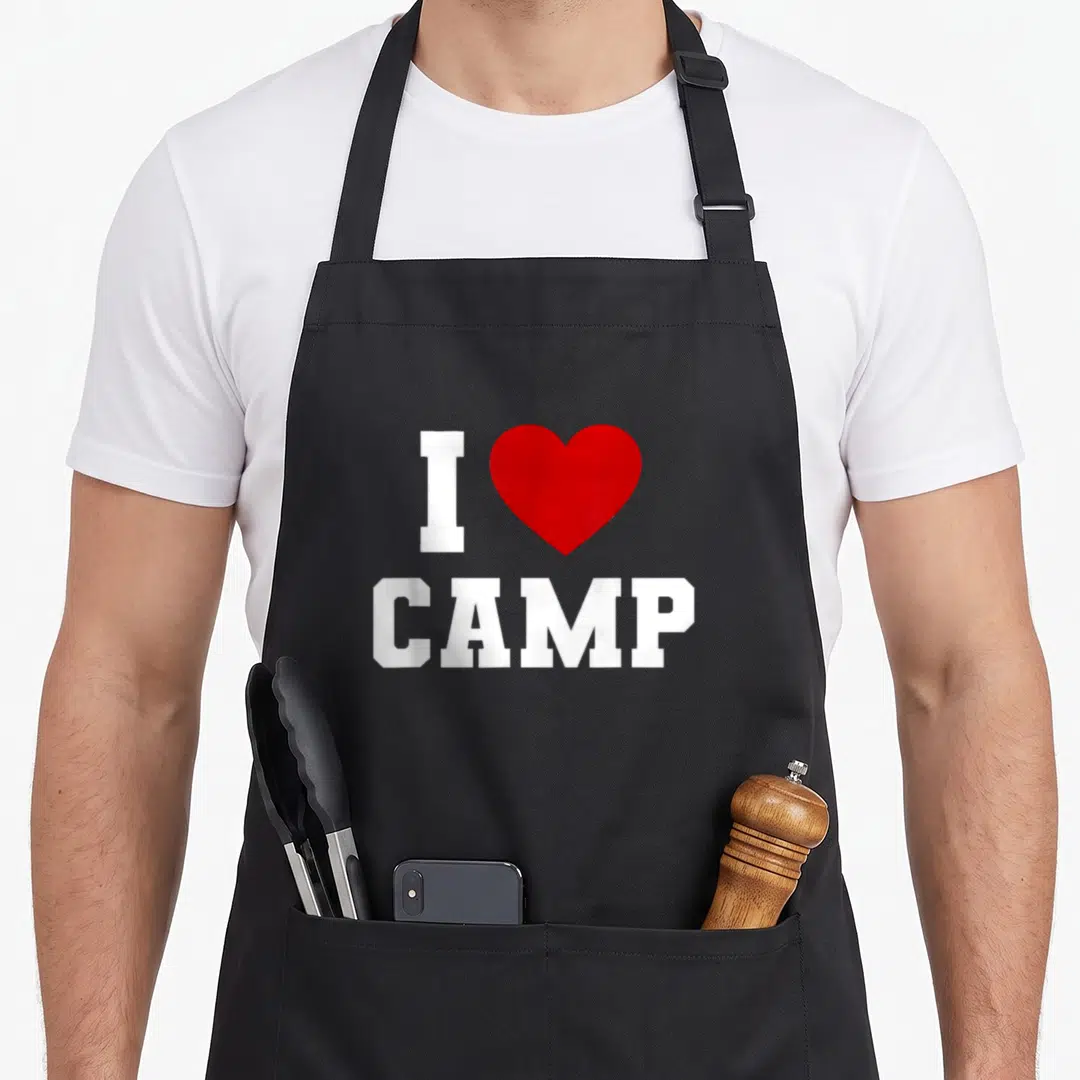 Summer camping apron - I CAMP text with red heart symbol on white background — shown on a black cotton canvas apron against a white background