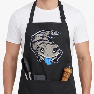 Blue skink apron - Cartoon salamander with grey body and blue tongue sticking out — shown on a black cotton canvas apron against a white background