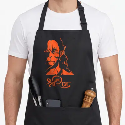 Hanuman ram apron - Orange stylized Hanuman head above Hindi text Jai Shri Ram — shown on a black cotton canvas apron against a white background
