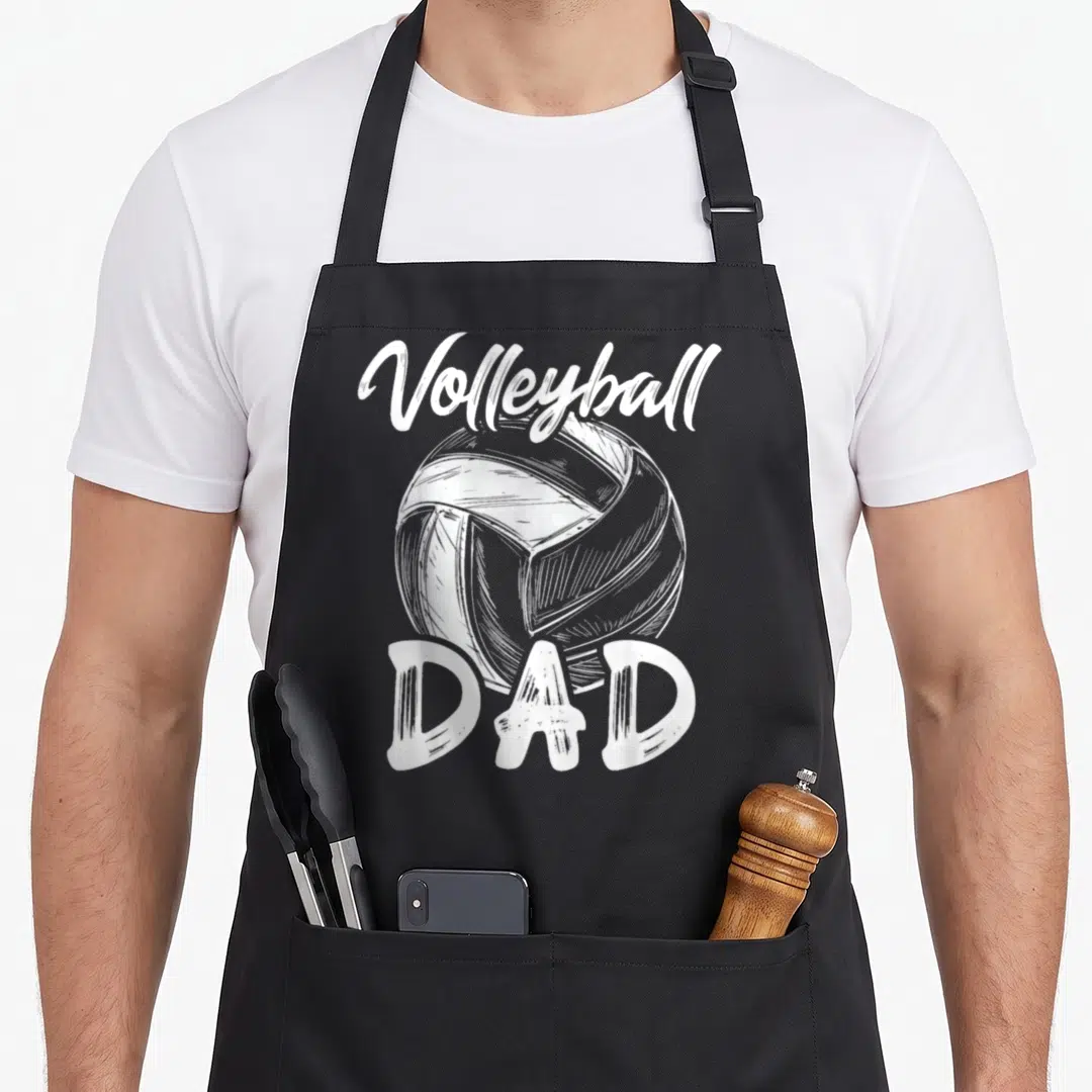 Player family aprons - White script Volleyball text above a sketched ball and block DAD letters — shown on a black cotton canvas apron against a white background