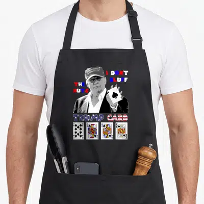 Trump ace apron - Poker player holding Ace of Spades with text I DON'T BLUFF THE NUTS and Trump Card lettering — shown on a black cotton canvas apron against a white background