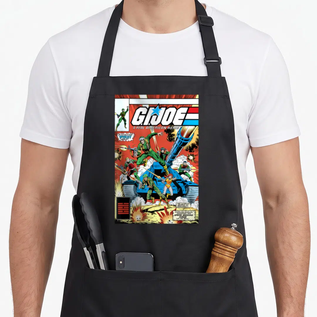 Joe i love cover apron - G.I. Joe comic cover with soldiers, tank, explosions, and text boxes in blue red green yellow — shown on a black cotton canvas apron against a white background