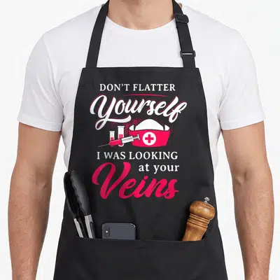 Technician phlebotomist nurse apron - DON'T FLATTER Yourself I WAS LOOKING at your Veins text with nurse hat syringe — shown on a black cotton canvas apron against a white background