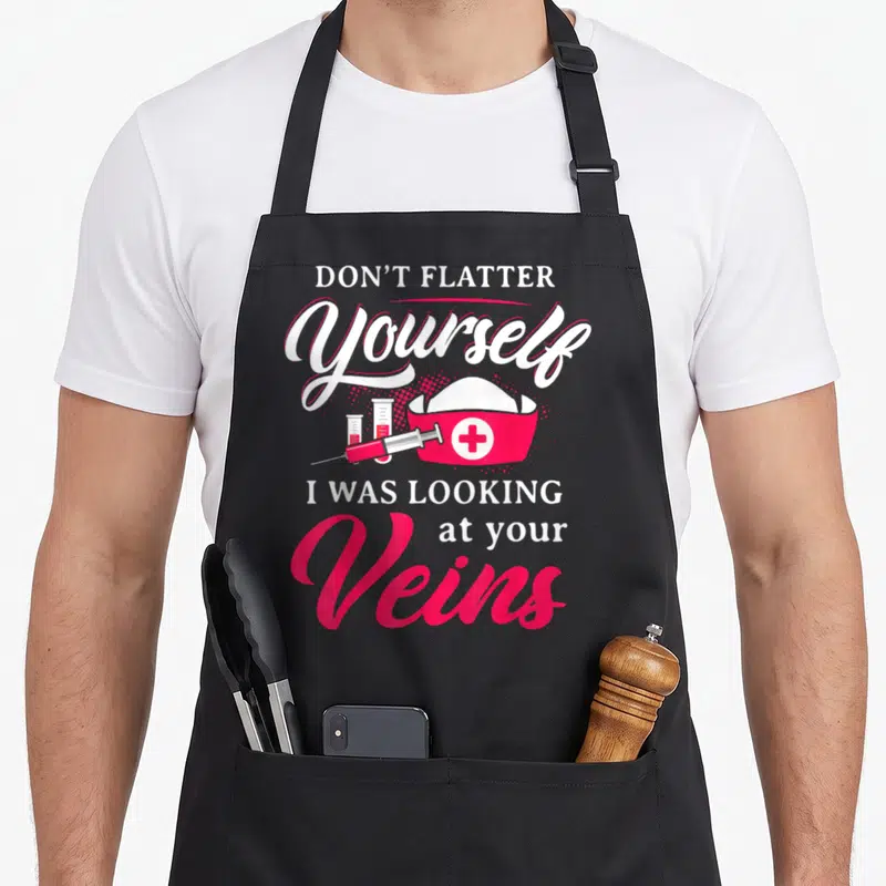 Technician phlebotomist nurse apron - DON'T FLATTER Yourself I WAS LOOKING at your Veins text with nurse hat syringe — shown on a black cotton canvas apron against a white background