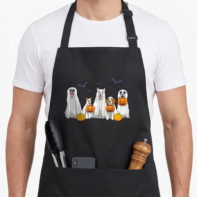 Dog halloween apron - Five white ghost dogs holding orange pumpkins with purple bats cartoon — shown on a black cotton canvas apron against a white background