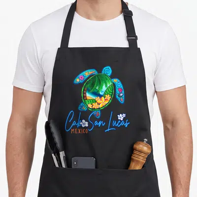 Lucas mexico apron - Cartoon sea turtle with tropical beach scene inside shell and blue Cabo San Lucas text — shown on a black cotton canvas apron against a white background