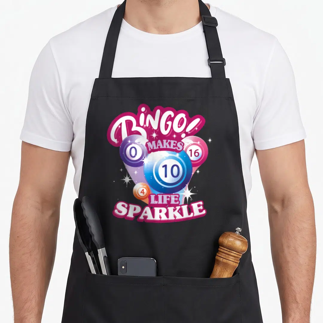Night bingo aprons - Four numbered bingo balls with BINGO text and white sparkles in magenta and blue — shown on a black cotton canvas apron against a white background