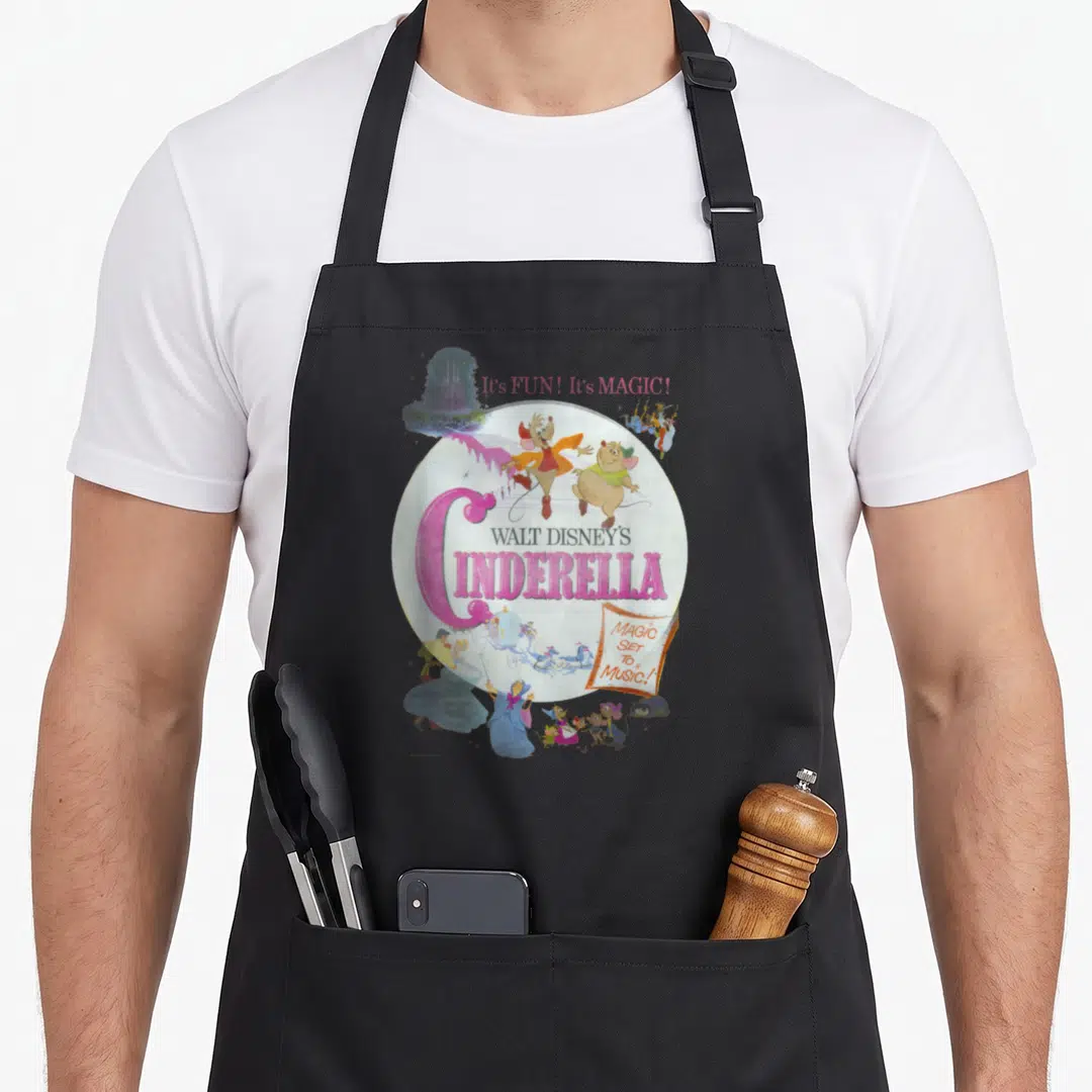 Poster cinderella apron - Vintage Cinderella movie poster art with pink text and cartoon characters in a circular layout — shown on a black cotton canvas apron against a white background