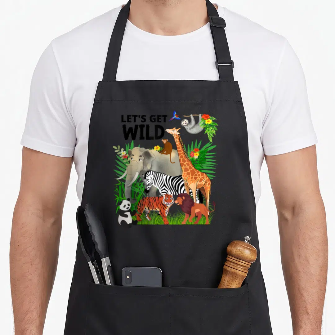 Wildlife safari birthday apron - Cartoon elephant giraffe zebra and lion under LETS GET WILD text surrounded — shown on a black cotton canvas apron against a white background