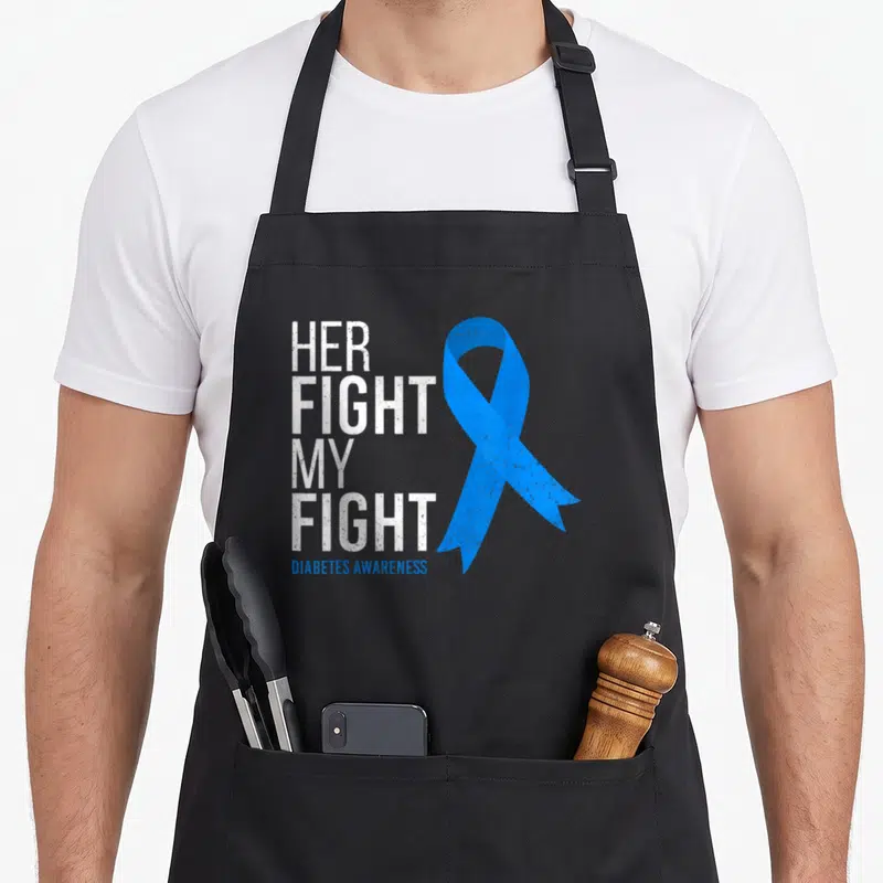 Fight diabetes awareness apron - Stacked white text reading HER FIGHT MY FIGHT next to a distressed blue awareness — shown on a black cotton canvas apron against a white background
