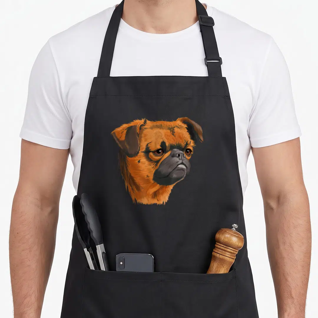 Funny brussel dog apron - Realistic orange and brown Brussels Griffon dog head portrait centered on grey background — shown on a black cotton canvas apron against a white background