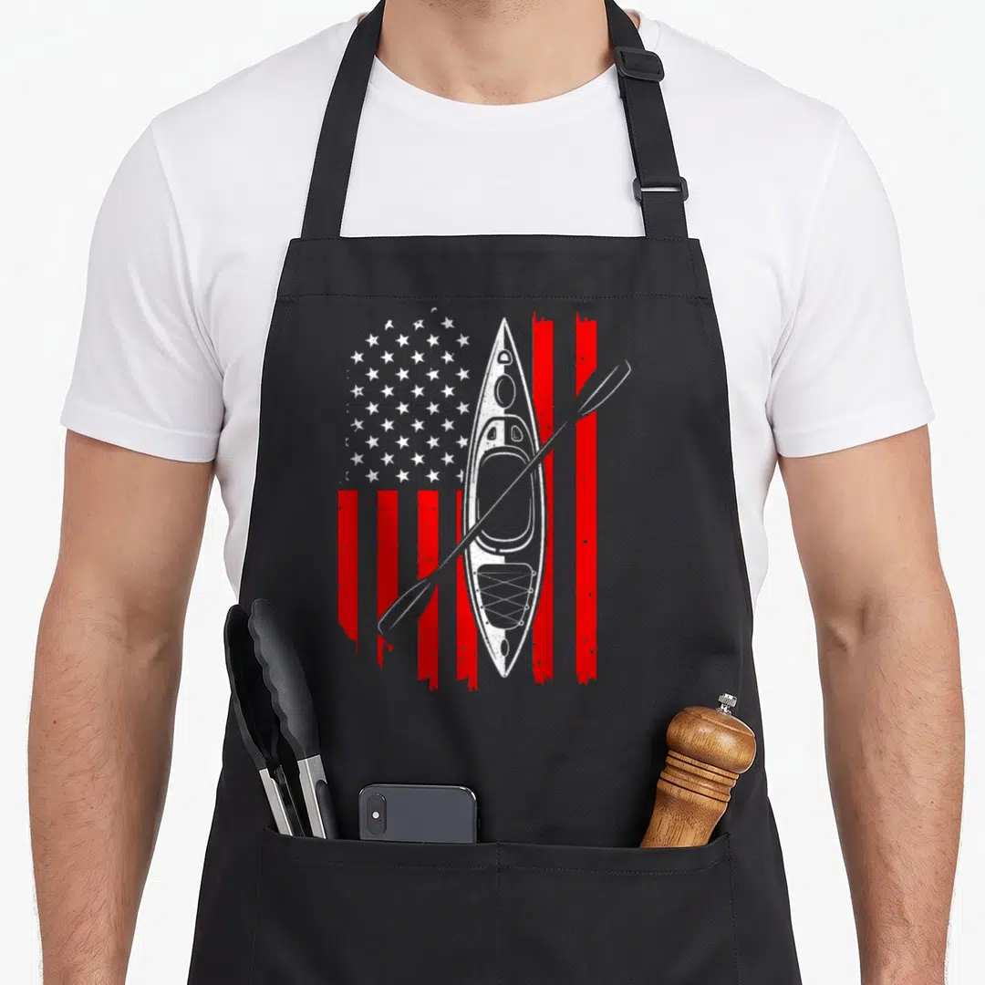 Kayaking american flag apron - White kayak and paddle superimposed over a distressed red and white USA flag graphic — shown on a black cotton canvas apron against a white background