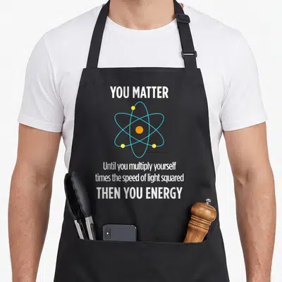 Matter experiment apron - YOU MATTER text and atom graphic with blue orbits and orange center — shown on a black cotton canvas apron against a white background