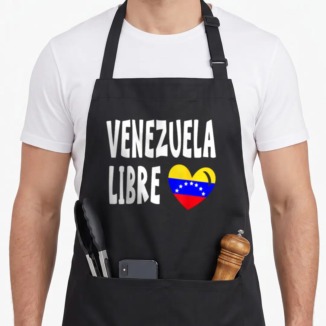 Libre pride apron - VENEZUELA LIBRE text beside a heart filled with yellow blue and red flag stripes and white stars — shown on a black cotton canvas apron against a white background