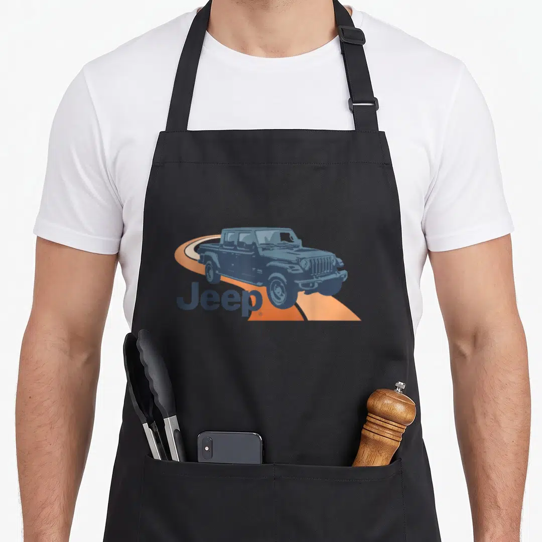 Jeep road apron - Blue-grey jeep silhouette on orange curved road with text in bottom left corner — shown on a black cotton canvas apron against a white background