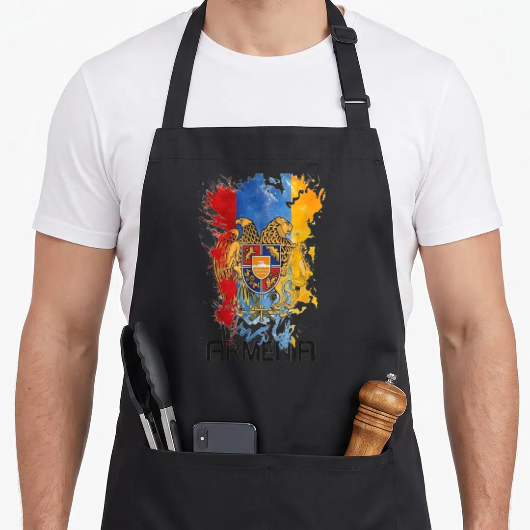 Clothe armenian apron - Coat of arms over red blue and yellow paint splatter with black ARMENIA text — shown on a black cotton canvas apron against a white background