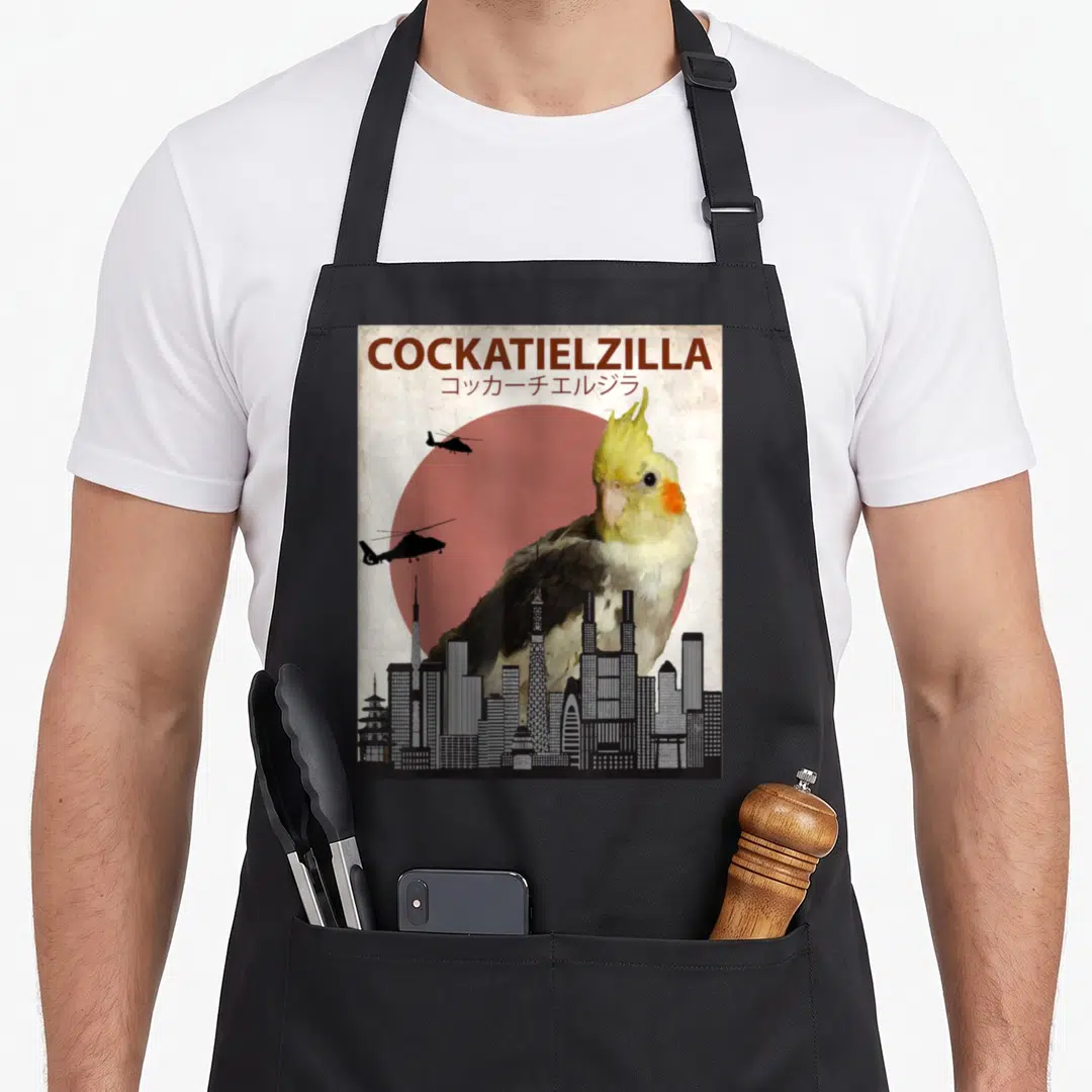 Cockatoo cockatiel lover apron - Giant cockatiel looms over black city skyline with red sun and two helicopters flying — shown on a black cotton canvas apron against a white background